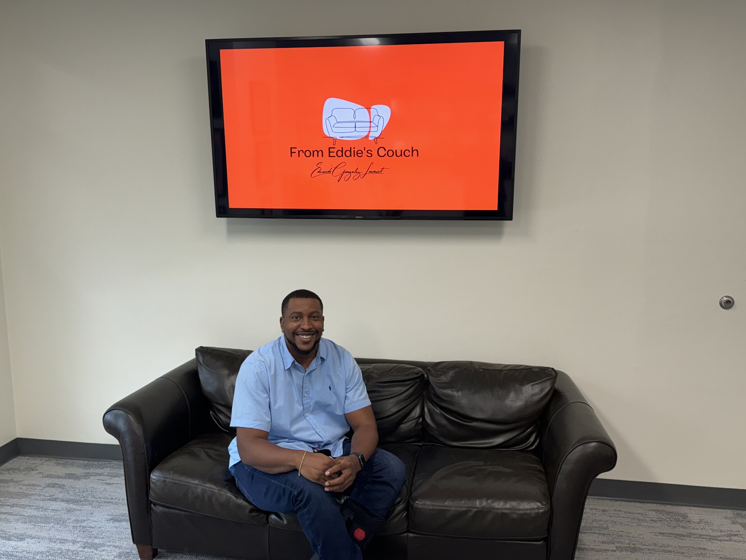 A visitor sitting on the couch in Eddie Gonzalez Loumiet's office