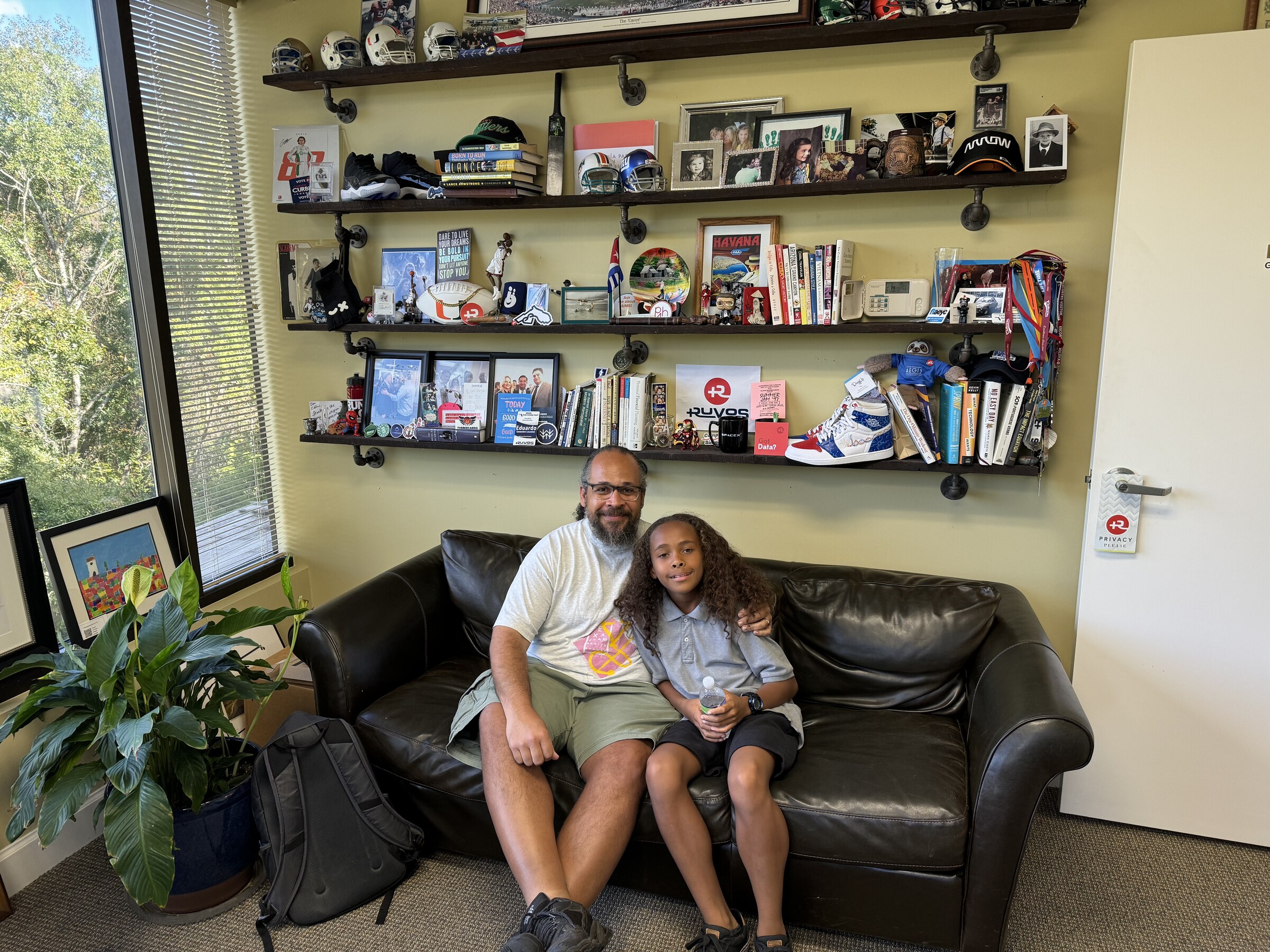 Eddie Gonzalez Loumiet sitting with a visitor on a couch in an office