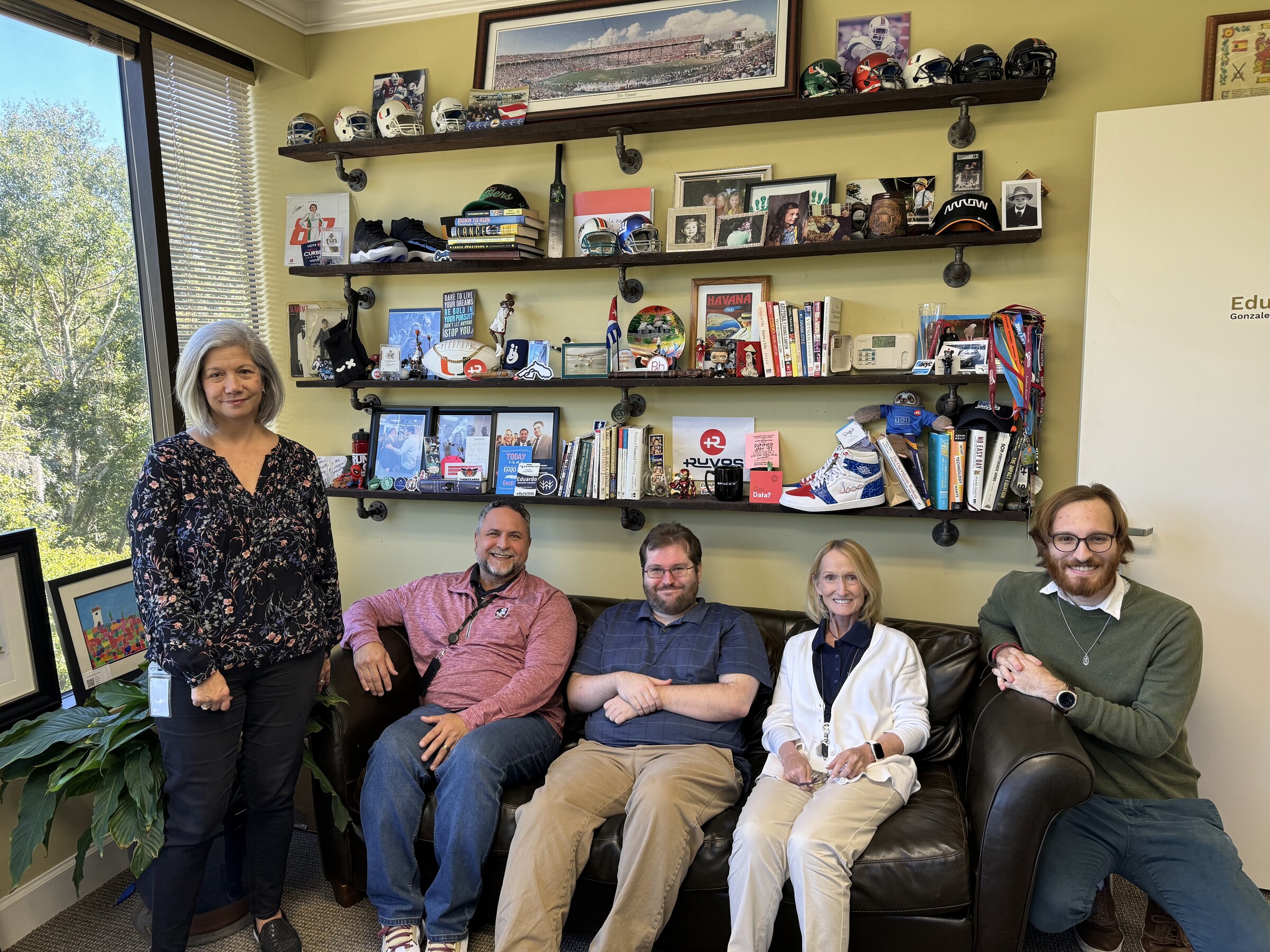 Eddie Gonzalez Loumiet sitting with a group of visitors on a couch in an office