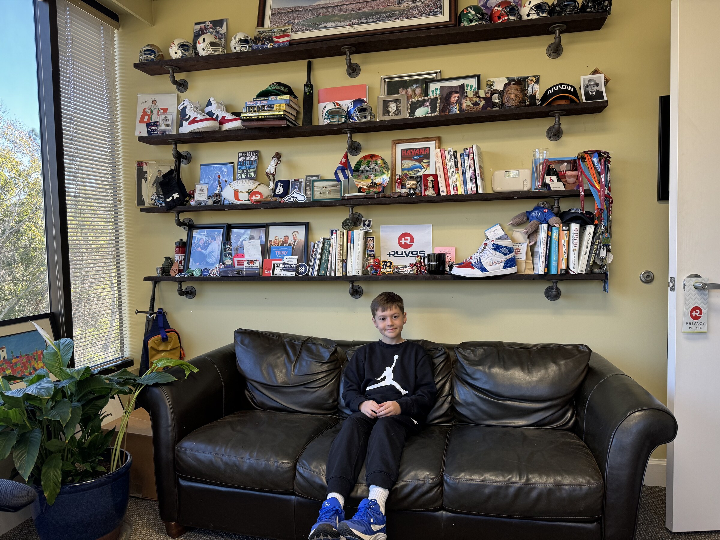 A young visitor sitting on the couch in Eddie Gonzalez Loumiet's office