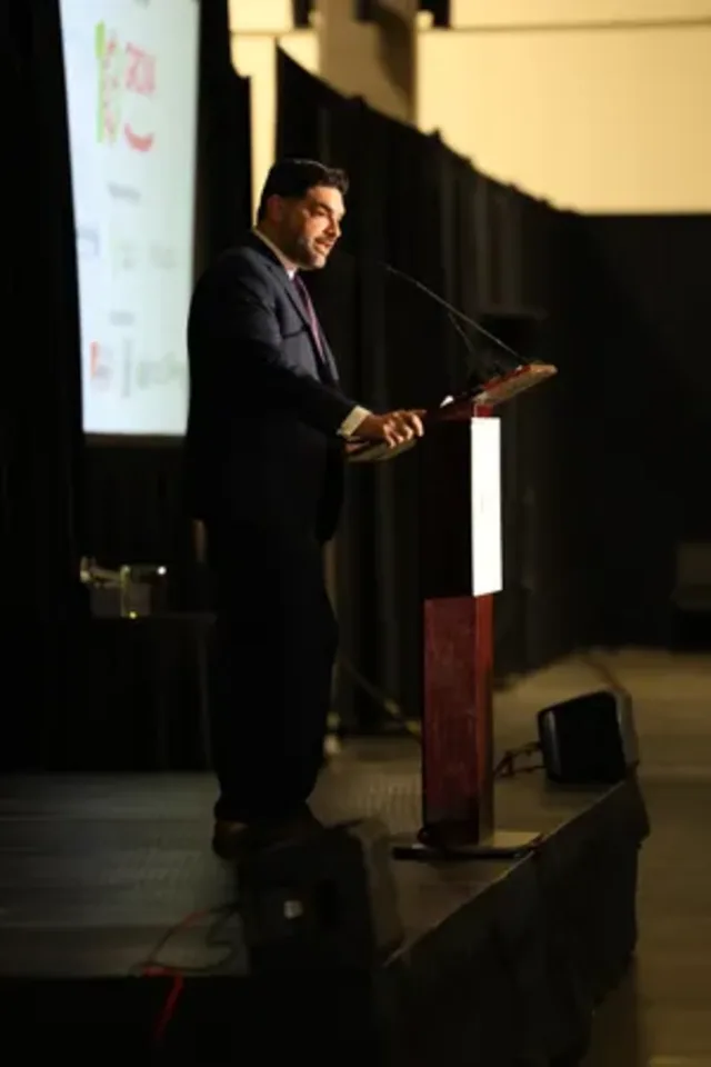 Eddie Gonzalez Loumiet delivering a keynote address at the podium during a public speaking engagement
